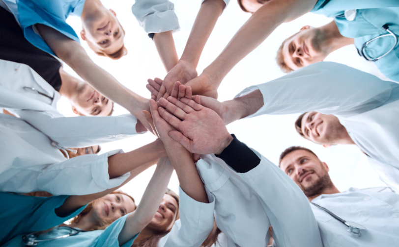 Group of health care professionals with hands forming a circle