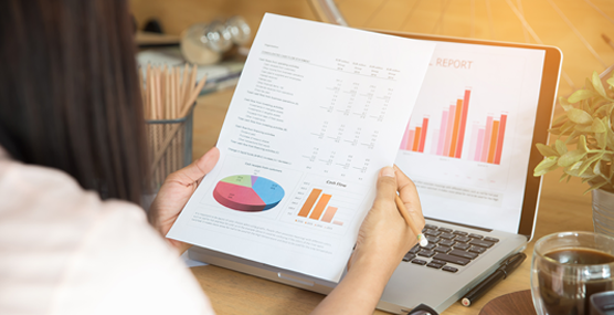 Woman looking at a report on paper with a graph on a laptop